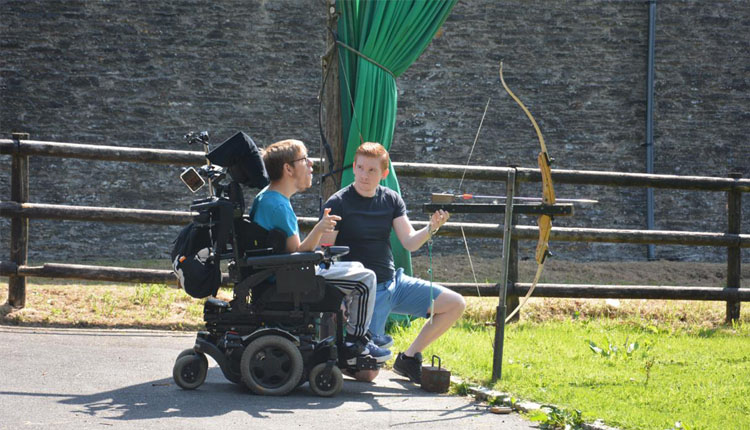 Boy in wheelchair learning archery with instructor at Calvert Exmoor